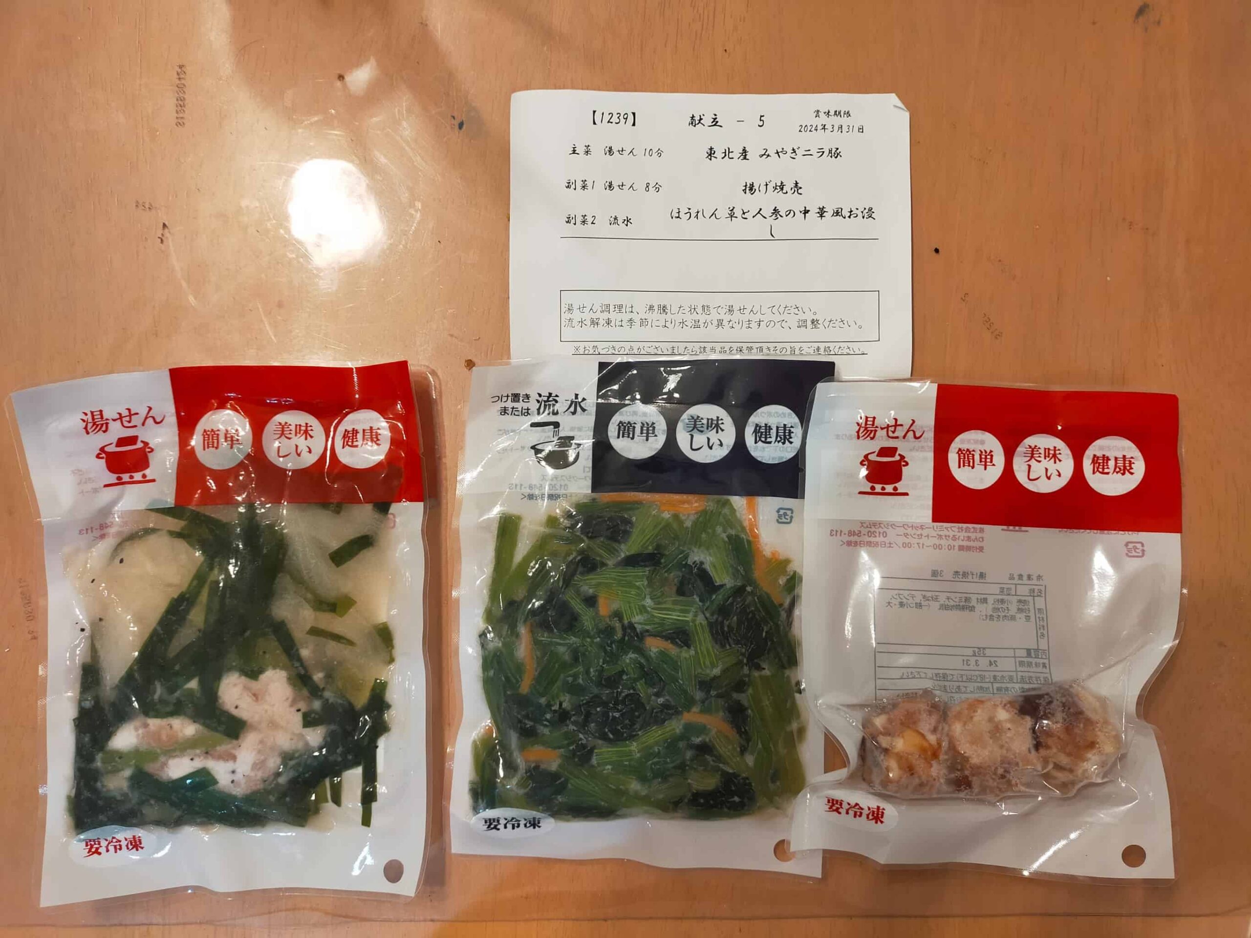 わんまいるの冷凍惣菜セット。左から「東北産みやぎニラ豚（湯せん解凍）」、中央「ほうれん草と人参の中華風お浸し（流水解凍）」、右「揚げ焼売（湯せん解凍）」の3品が並ぶ。