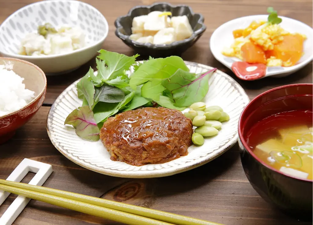 つるかめキッチン「カロリー制限気づかい御膳」ハンバーグ定食。ハンバーグと枝豆、野菜サラダ、副菜、ご飯、味噌汁のバランスセット。